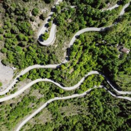 Aerial view of winding hairpin roads through alpine forest